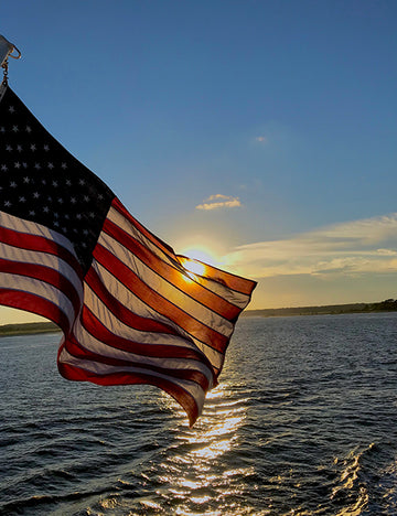 American flag waving in the wind on a lake 
